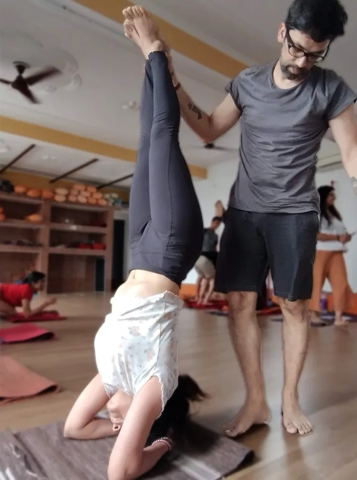 Kamal assisting a student in an inversion during class